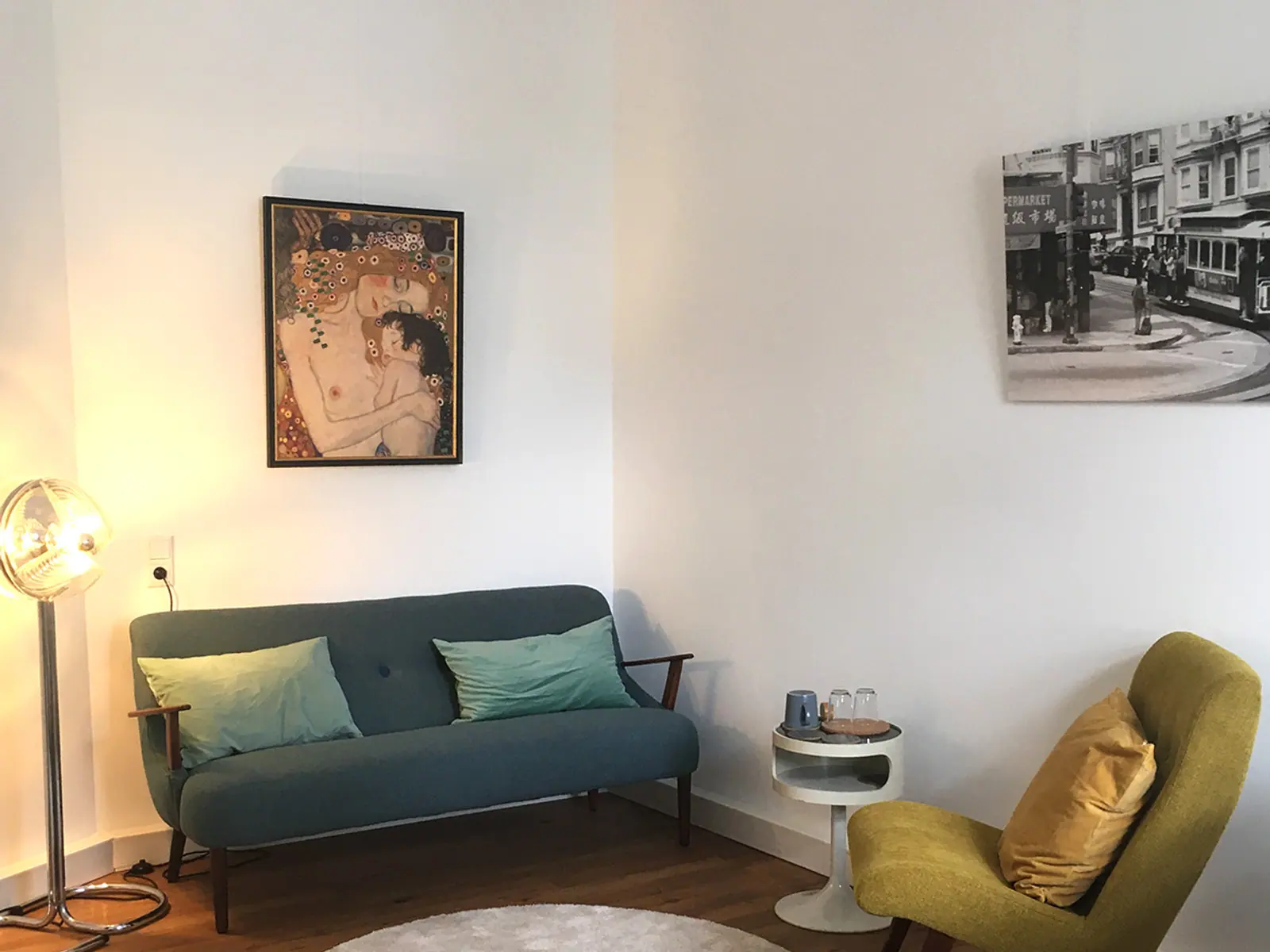 Ruhiger Therapieraum der Praxis Haberecht mit petrolfarbenem Sofa, Sessel und warmem Holzboden.