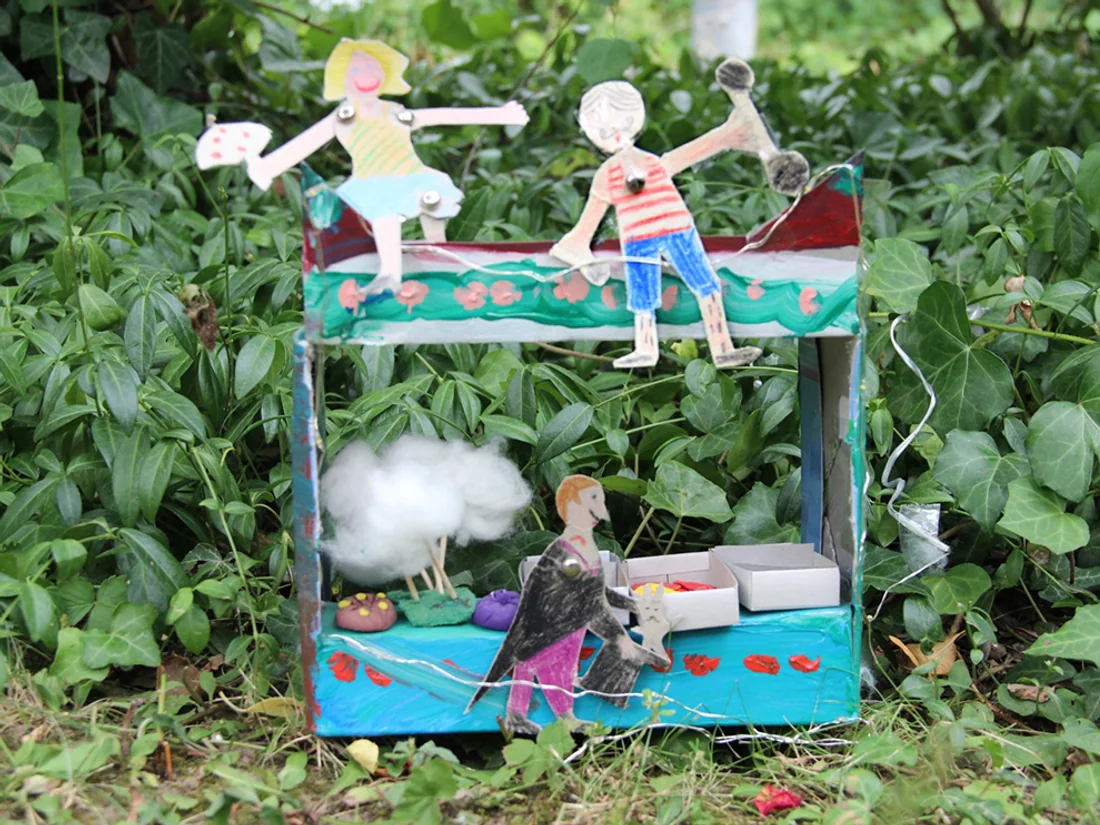 Selbst gebasteltes Guckkasten-Theater eines Kindes mit gemalten Papierfiguren, entstanden in der Therapie.